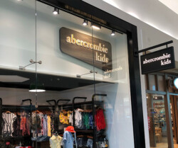 Storefront of Abercrombie Kids in a shopping mall, displaying children's clothing on racks inside the store.