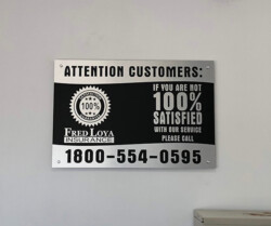 Sign that reads, "Attention customers: If you are not 100% satisfied with our service, please call 1-800-554-0595. Fred Loya Insurance. 100% Satisfaction Guarantee.