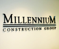 A wall sign reads "Millennium Construction Group" in large, metallic letters with horizontal lines separating the words.