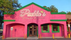 Bright pink and green exterior of Puebla's Mexican Kitchen, featuring distinct green accents and large signage above the entrance.