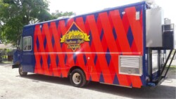 A brightly painted red and blue food truck with the sign "Lil' Auntie's Southern Style Cooking" is parked on a street.