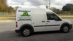 A white van with signage for "Green Ape Landscape" and the slogan "Go Ape for Your Landscape." Contact number 832-877-8405 is displayed on the side. The van is parked on a street with trees and fencing in the background.